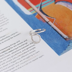 Dettaglio anello in argento S925 con trama a foglio d'alluminio su una pagina di libro