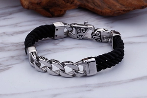 Close-up of men's titanium steel totem bracelet with black nylon braided rope on marble