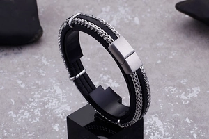 Detail of woven black leather men's bracelet with stainless steel chains and brushed clasp