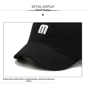 Close-up of black baseball cap featuring a white embroidered letter m and textured fabric