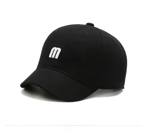 Close-up of black cotton short-brim baseball cap featuring white 3D letter M embroidery