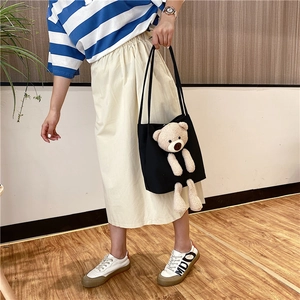 Détail d'un sac cabas en toile noire avec un ours en peluche 3D et de longues anses