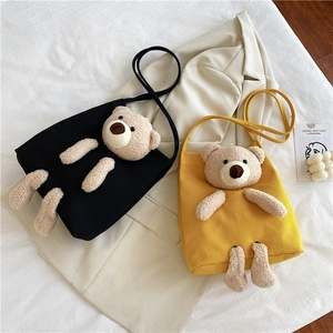 Détail de sacs fourre-tout en toile noir et jaune avec décoration d'ours en peluche