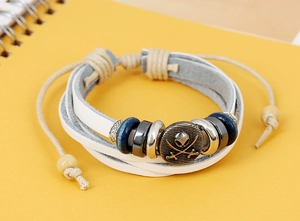 Detail of woven leather bracelet featuring a metal skull plate and wooden beads accent