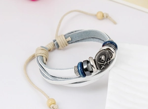 Detail of white braided leather bracelet with pirate skull medal and blue ceramic beads