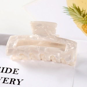 Close-up of marble-textured cream hair claw clip with elegant pearlescent finish