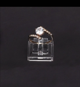 Dettaglio anello in oro rosa con diamante bianco su supporto in acrilico