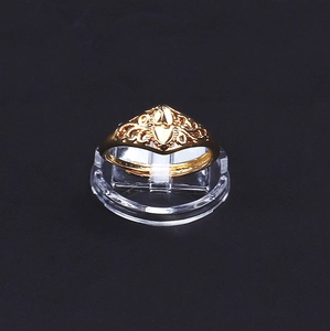 Dettaglio di un anello dorato regolabile con motivi intagliati su supporto chiaro