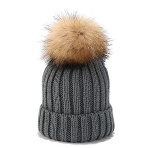 Detailaufnahme der grauen Strickmütze mit großem flauschigem braunem Pelzbommel Akzent