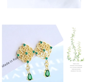 Detailed macro view of gold Chinese style emerald teardrop tassel earrings on white card