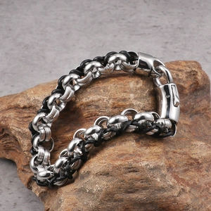 Men's retro stainless steel and black woven leather bracelet on a brown rock