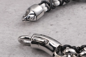 Macro detail of silver snake head metal clasp on a black braided leather bracelet