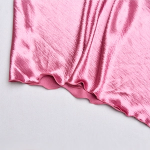 Gros plan sur l'ourlet en satin rose montrant le tissu brillant et la texture ondulée