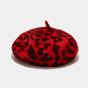 Detail shot of the plush faux fur texture and black leopard print on a red beret hat