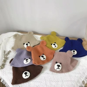 Detailed knit texture of colorful bear ear bucket hats for infants on white linen background