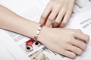 Rose gold heart bracelet with metal mesh strap on model over fashion magazine