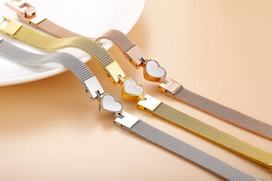 Detailed view of heart-shaped charms on mesh bracelets in silver, gold, and rose gold