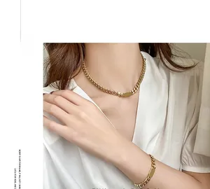 Detailed view of a gold Cuban link necklace and bracelet set with polished metal plates