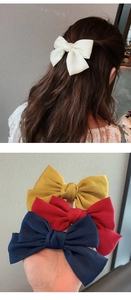 Dettaglio di eleganti fermagli per capelli con fiocco in raso panna, giallo, rosso e blu