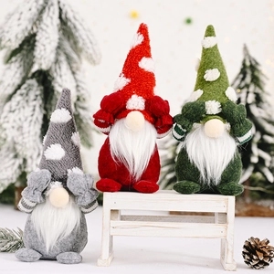 Three festive Christmas gnomes in red, grey, and green sitting on a white wooden bench