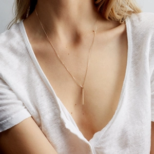 Minimalist gold bar pendant necklace in 316L stainless steel on a model with white linen shirt