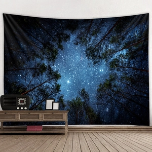 Detailed view of large starry sky forest tapestry hanging in a modern bedroom setting