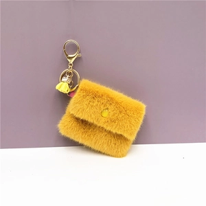 Detail of yellow plush mini coin purse with golden lobster clasp and decorative tassel
