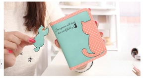 Close-up of mint green and pink polka dot wallet with cute cat pendant and pattern