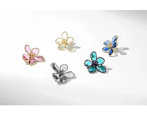 Detail showing five-petal crystal flower brooches in various colors on white background