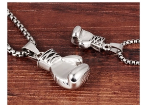 Macro shot of large and small silver boxing glove pendants on dark wood texture background