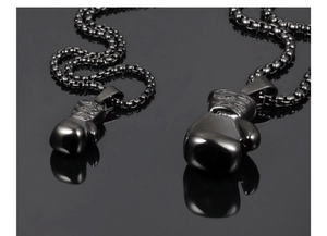 Detail view of two black titanium steel boxing glove pendants in small and large sizes