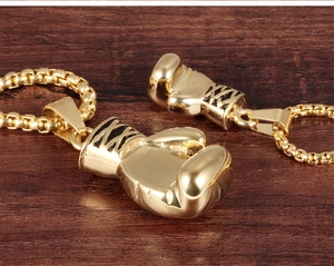 Macro shot of gold-tone solid fist pendants on a rustic dark wood background