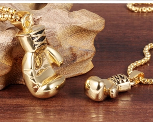 Macro shot of gold boxing glove pendants on textured wood with a polished metal finish