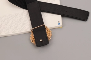 Close-up of black elastic belt featuring a golden hollow buckle and faux leather detail