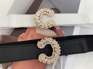 Detail of black and white elastic belts featuring sparkling rhinestone-inlaid gold C-buckles