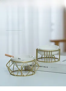 Detail view of white ceramic ashtray set with golden geometric metal stands on a book