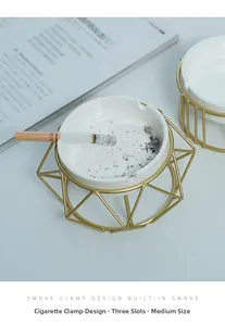 Detail of modern ceramic ashtray with gold geometric metal base and three cigarette slots