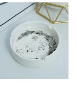 Close-up of minimalist white ceramic ashtray with gold geometric metal frame accent