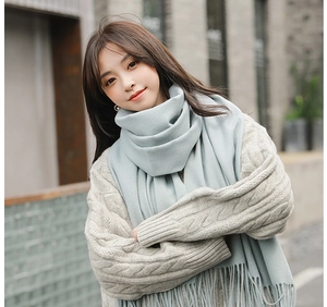 Close-up of soft light blue cashmere scarf with elegant fringe detail and thick texture