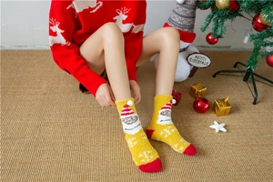 Close-up of yellow coral fleece Christmas socks with 3D Santa Claus and pom-poms