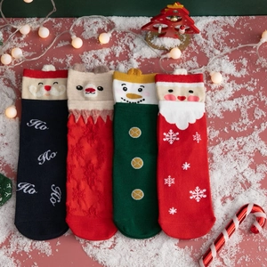 Close-up of four knitted Christmas socks with Santa and Reindeer on snowy festive background