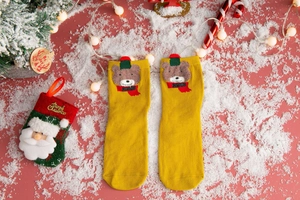 Detail of yellow Christmas sock with 3D teddy bear applique on snowy festive background