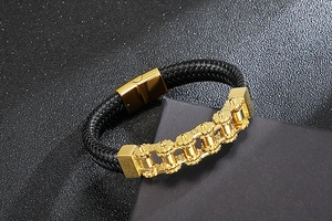 Macro shot of men's black leather braided bracelet with gold gear-style chain clasp
