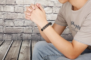 Close-up of industrial style black metal chain and leather bracelet on male wrist