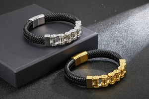 Detail of woven black leather bracelets with gold and silver gear chains in a gift box