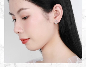 Close-up of a silver round stud earring with small diamonds worn by a female model