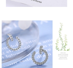 Macro shot of silver C-shaped crystal earrings with polished finish on blue background