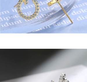 Macro detail of gold and silver horseshoe earrings inlaid with sparkling clear zircons