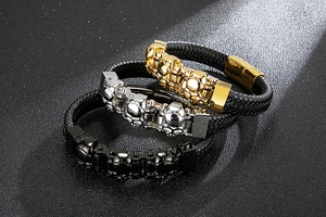Detail of punk style skull bracelets with braided leather straps in gold, silver, and black