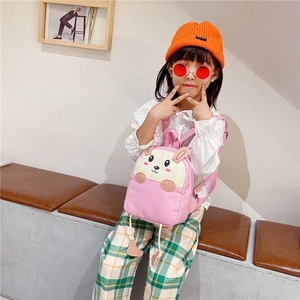 Pink canvas toddler backpack with cute bunny ears shown on model in indoor setting